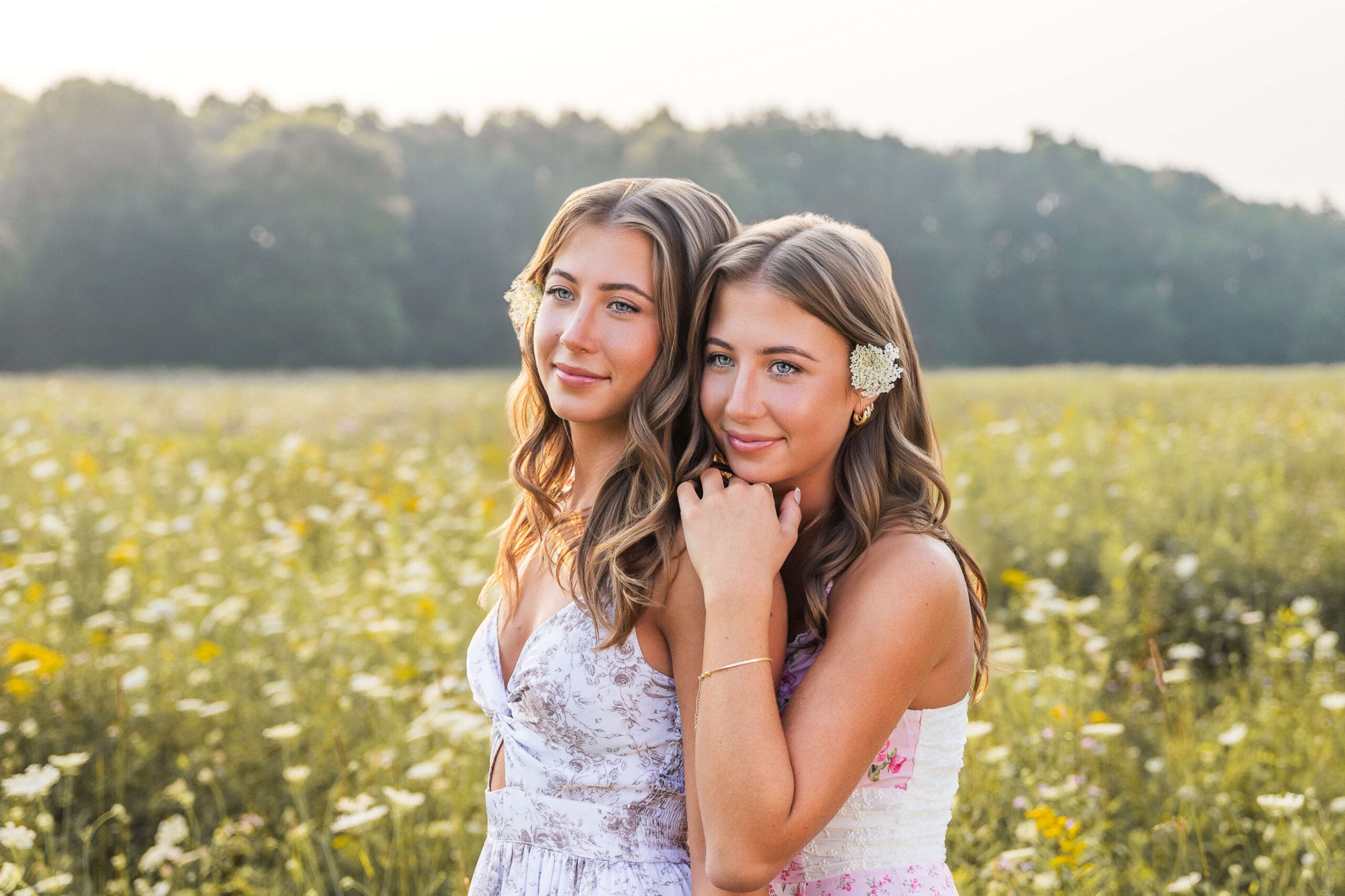 Twin sisters hang on each other in a wildflower field in floral print dresses at sunset after finding detroit promise